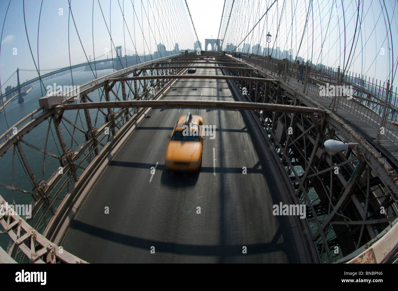 A Yellow Cab taxi on the Brooklyn Bridge between Manhattan and Brooklyn over the East River. New York Stock Photo