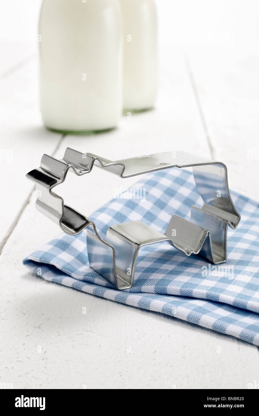 Kuhfoermige Ausstechform, im Hintergrund zwei Milchflaschen Stock Photo
