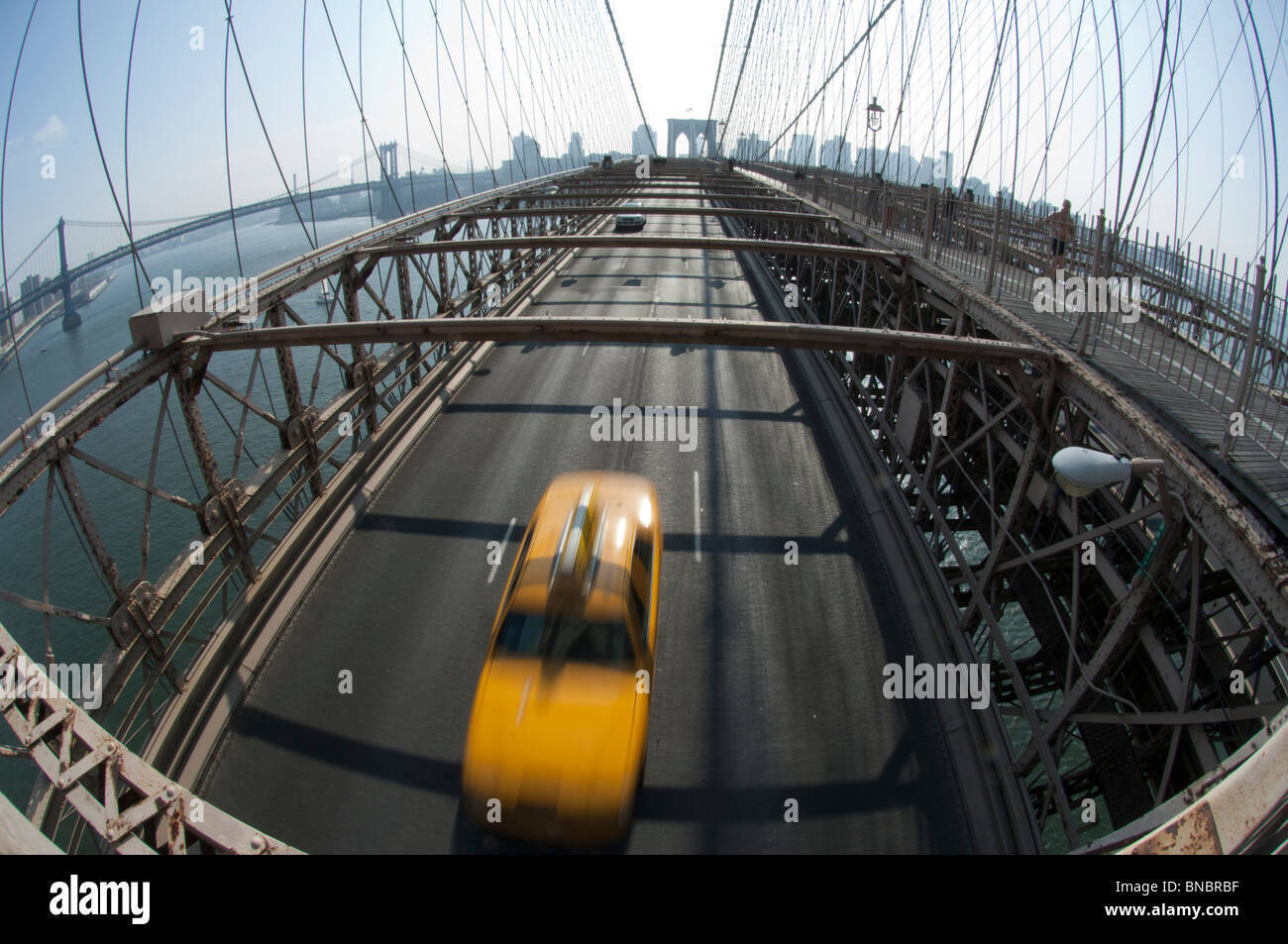 A Yellow Cab taxi on the Brooklyn Bridge between Manhattan and Brooklyn over the East River. New York Stock Photo