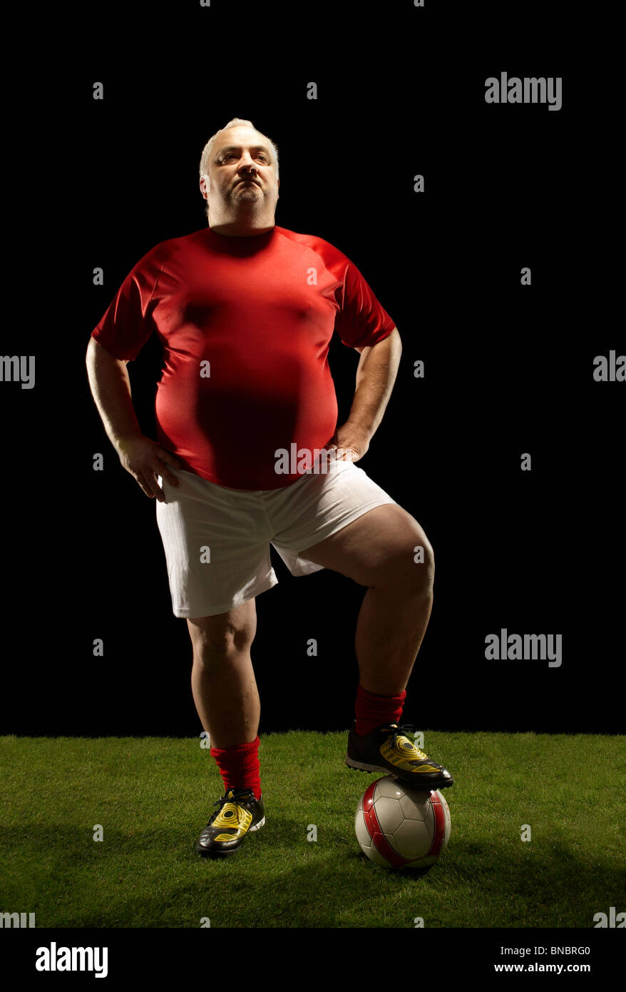 Large sportsman with foot on football Stock Photo
