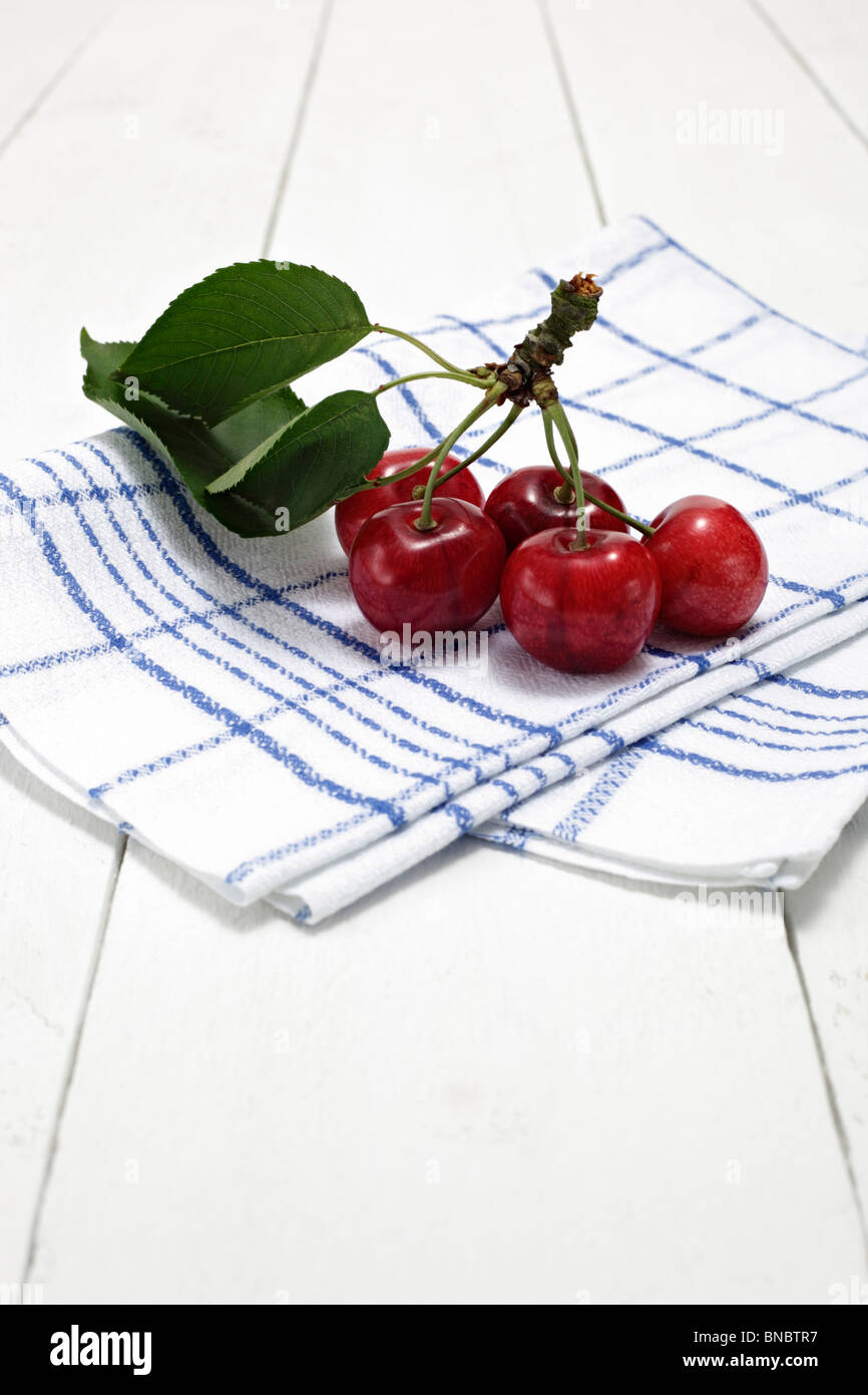 Suesskirschen mit Kirschbaumblaettern auf Geschirrtuch Stock Photo