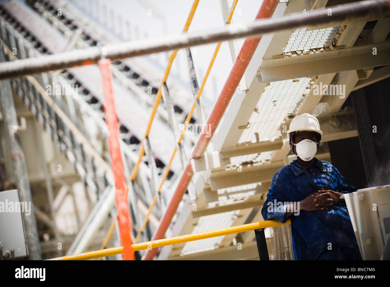 A mine worker rests against the railing of the crushing mill at the Youga gold mine Stock Photo