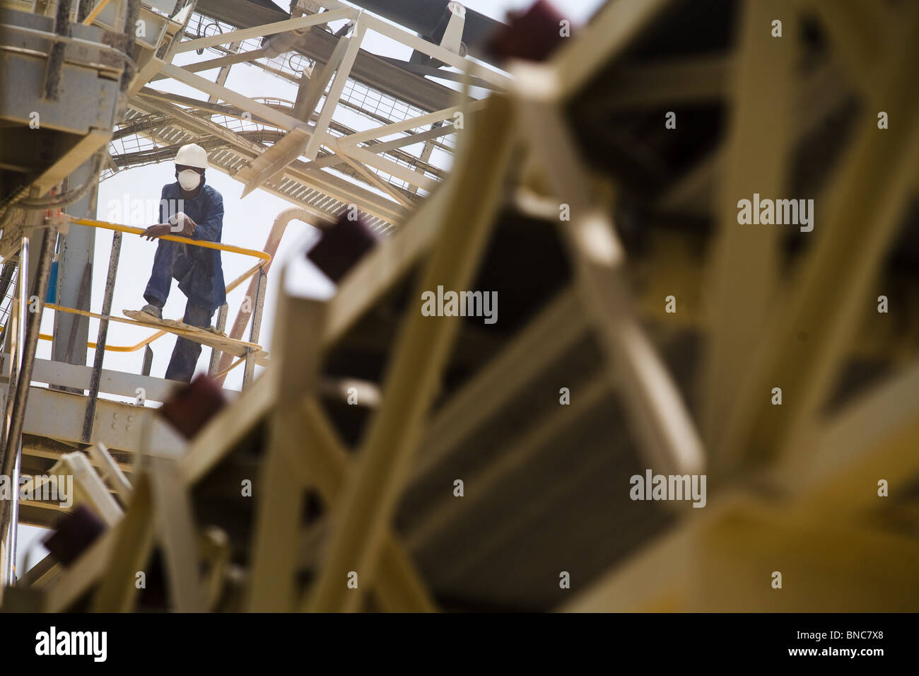 A mine worker rests against the railing of the crushing mill at the Youga gold mine Stock Photo