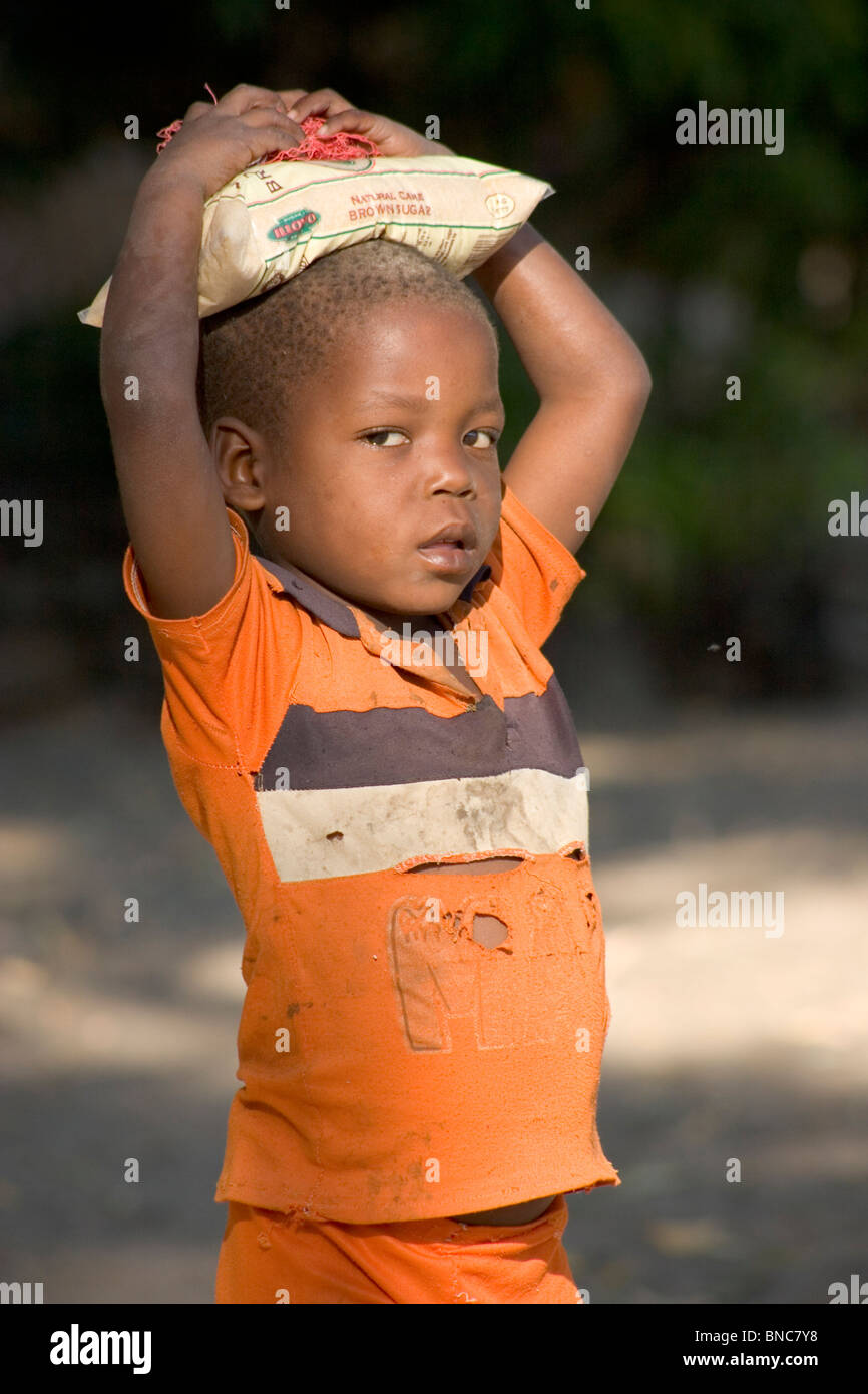 Malawian boy carrying bag of sugar on his head, Chizumulu Island. Stock Photo