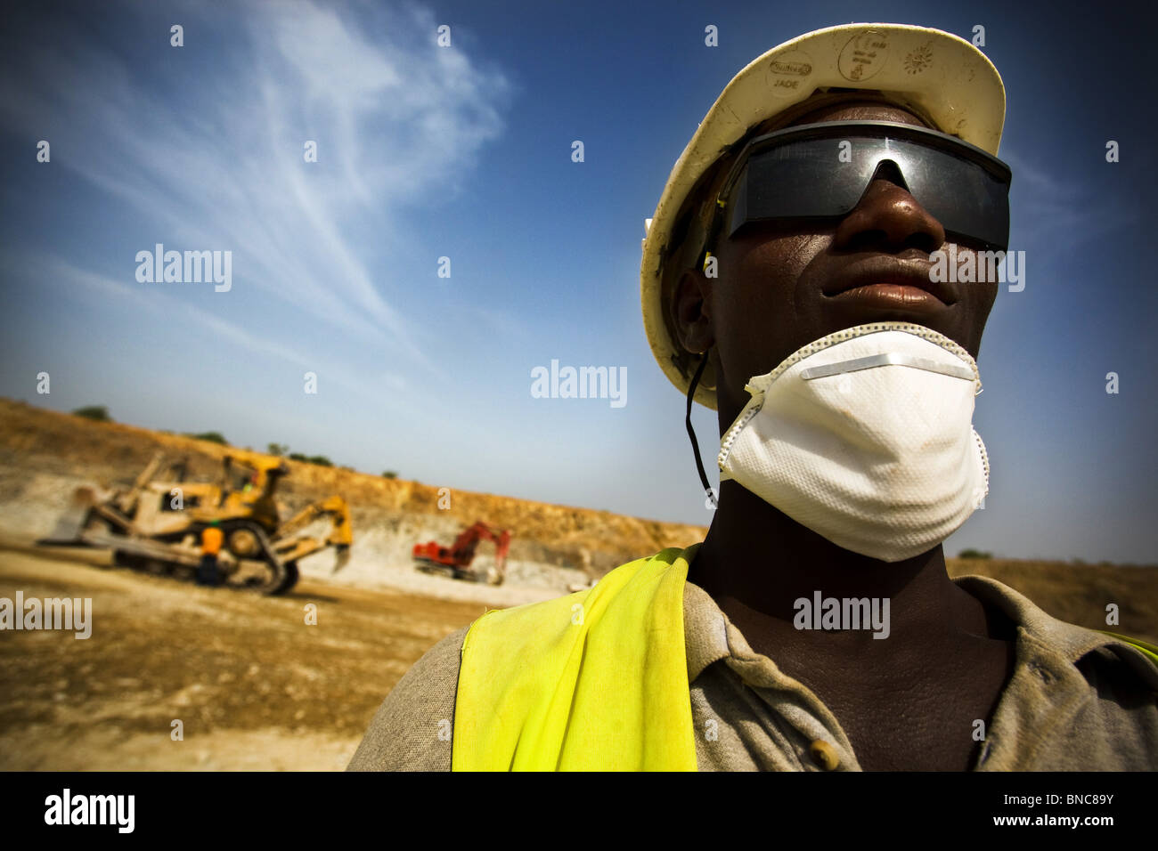 A mine worker watches over excavation operations in the main pit of the Youga gold mine Stock Photo