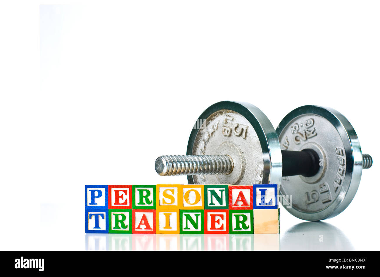 Colorful children's blocks spelling PERSONAL TRAINER with dumbbell weights in background Stock Photo