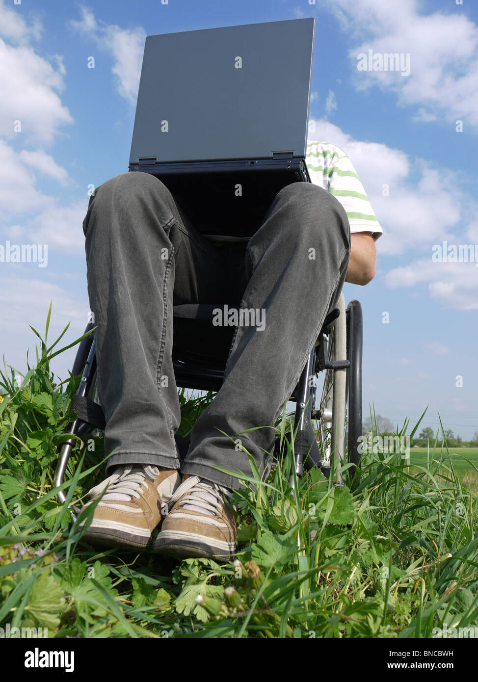Handicapped man on wheelchair using laptop outdoors Stock Photo