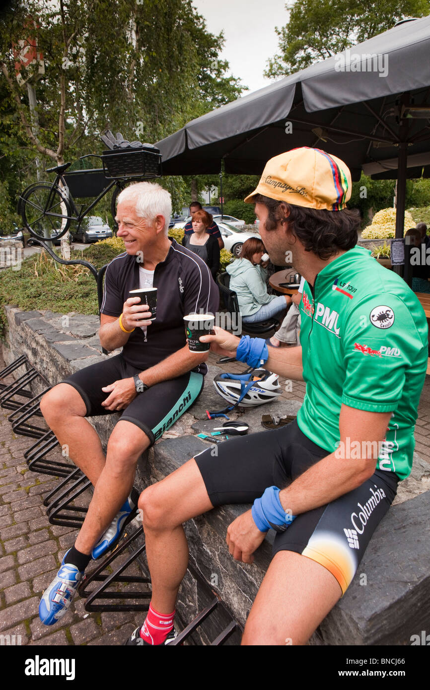 UK, Wales, Snowdonia, Betws y Coed, two older male cyclists resting with paper cups of takeaway coffee Stock Photo