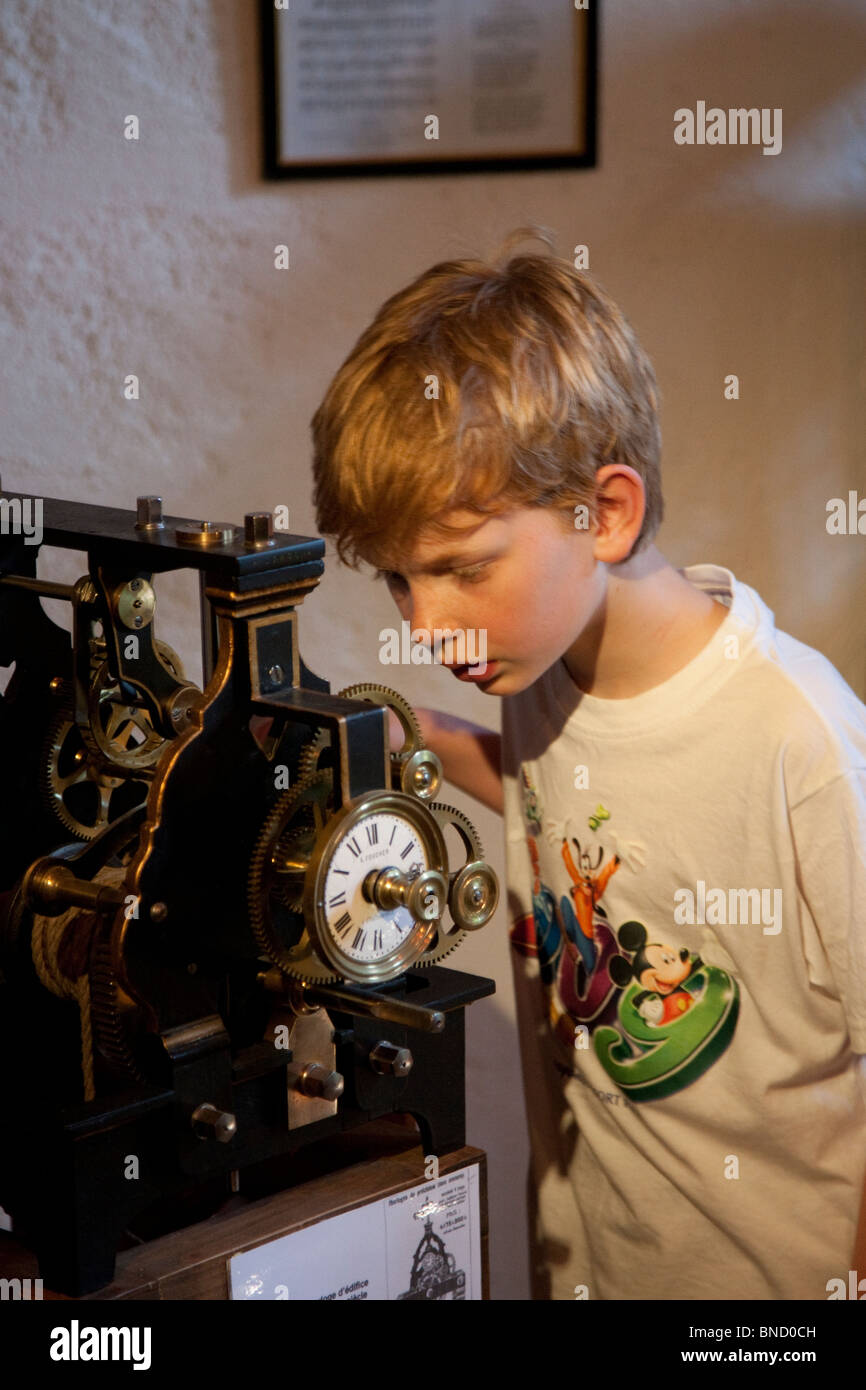 Boy looking at a clock mechanism in a museum in a French village. Stock Photo
