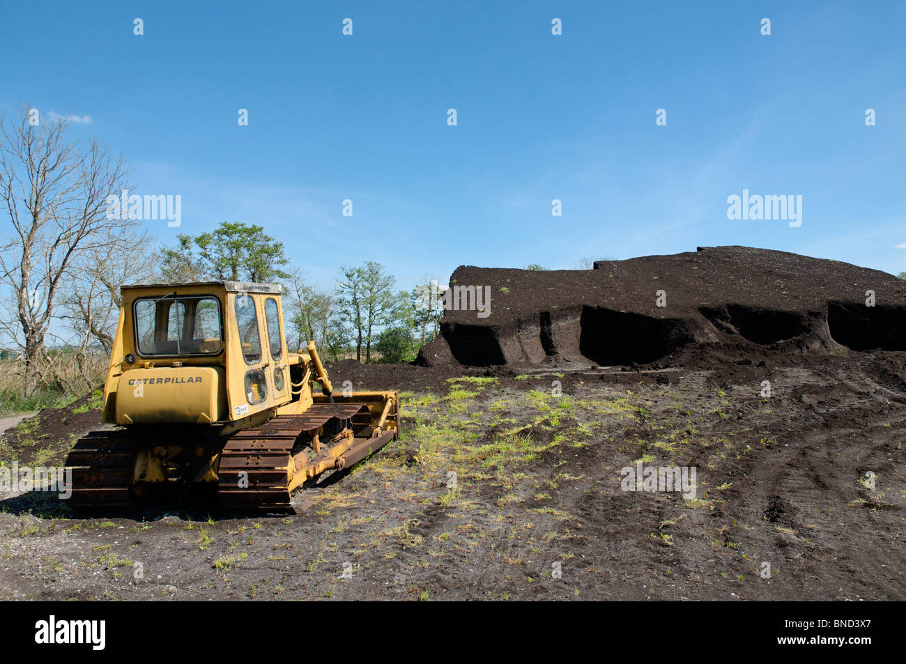 Peat cutting operation on the Somerset levels with a large stockpile of peat nearby Stock Photo