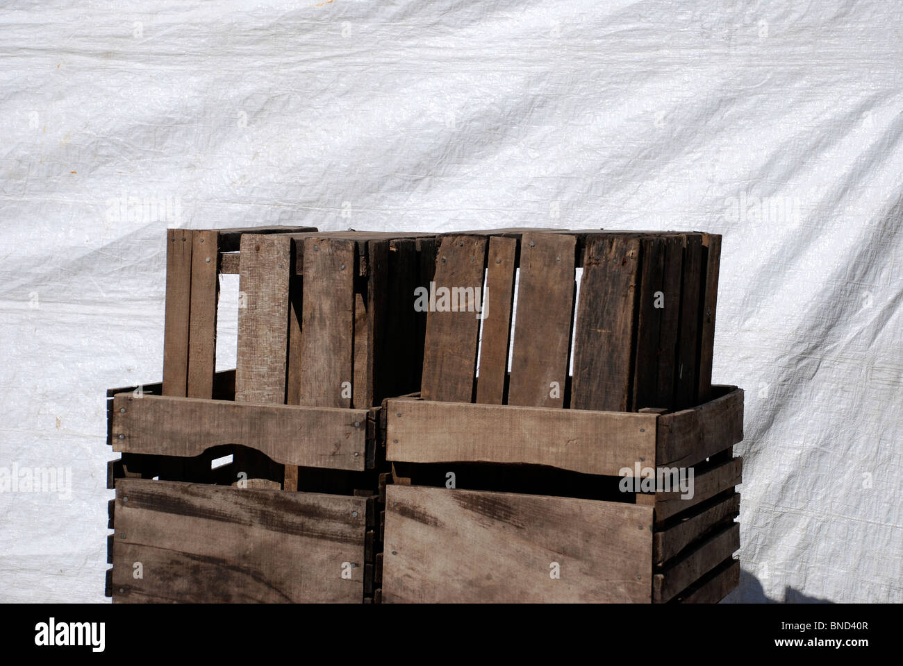 Empty vegetable crates at the farmers' market against white tarp. Stock Photo