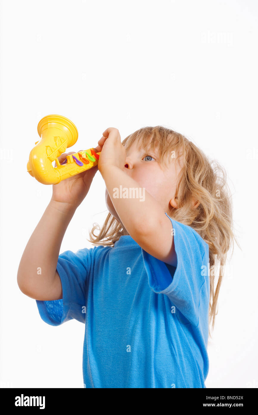 boy with long blond hair playing with toy saxophone Stock Photo