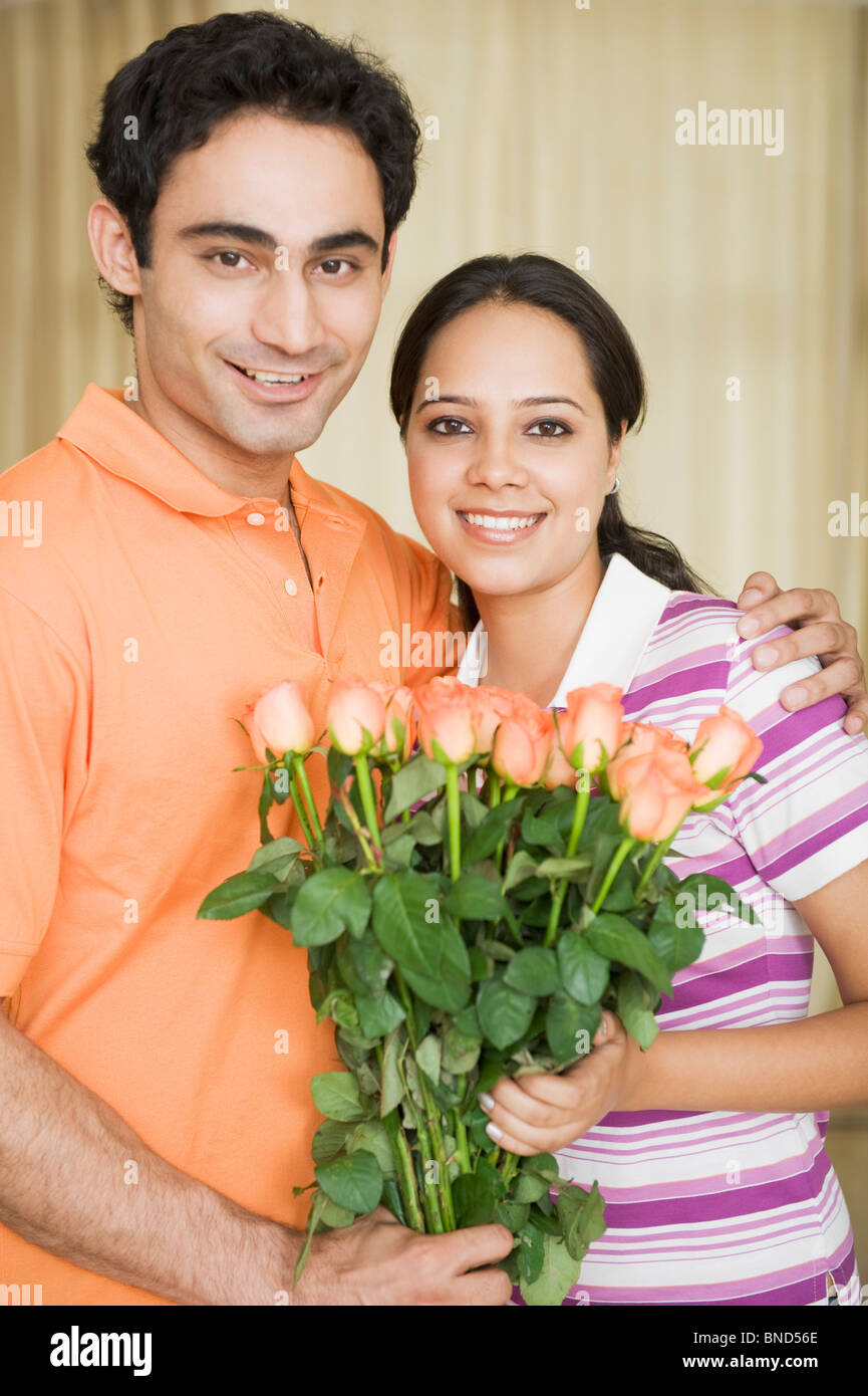 Couple holding a bouquet of flowers and smiling Stock Photo - Alamy