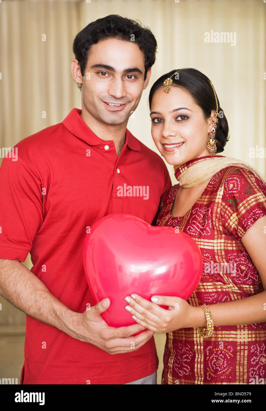 Couple holding a heart shape balloon and smiling Stock Photo - Alamy