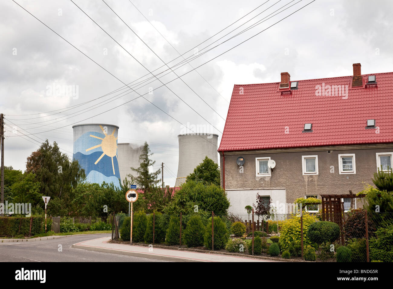 Residential houses in front of a brown coal power plant with sun motive on its chimney in Bogatynia, Poland Stock Photo