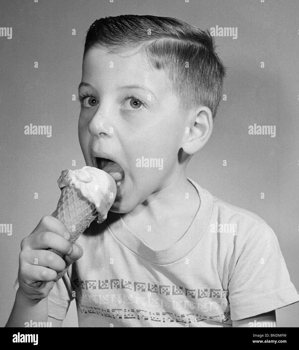 Portrait of boy eating icecream,  studio shot Stock Photo