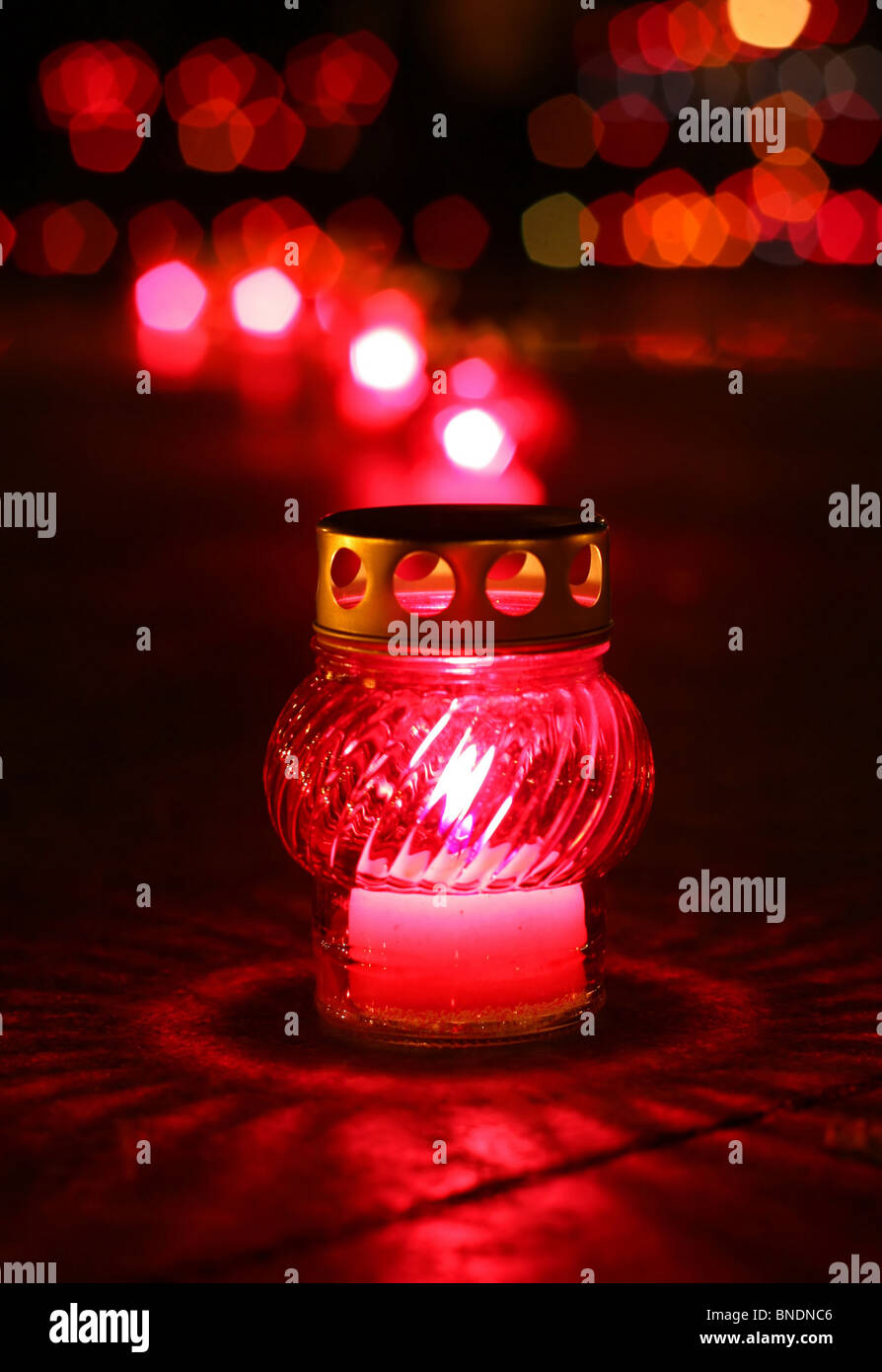 Closeup of red burning votive candle in lights background Stock Photo