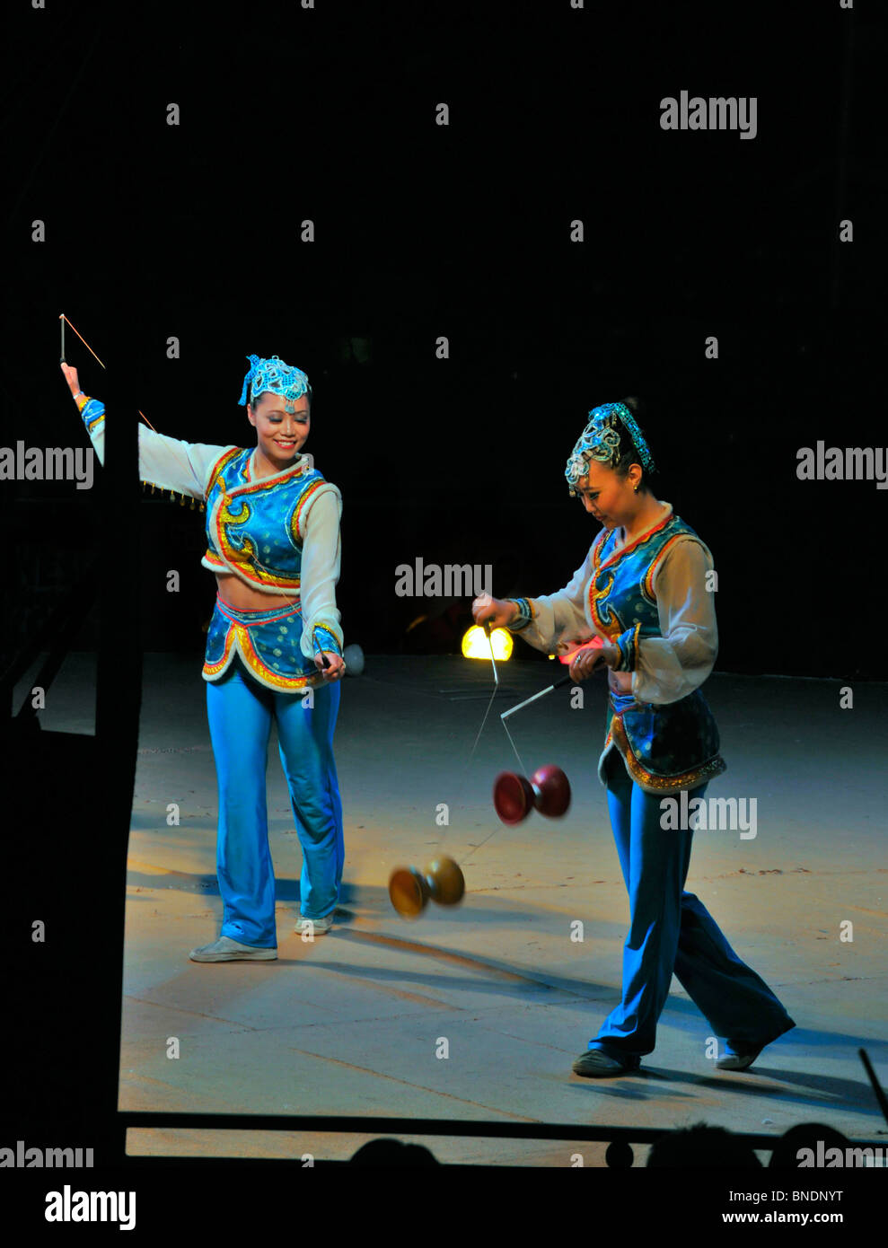 Chinese circus performers skillfully play with diabolos - Chinese wooden  spinning tops. Stock Photo