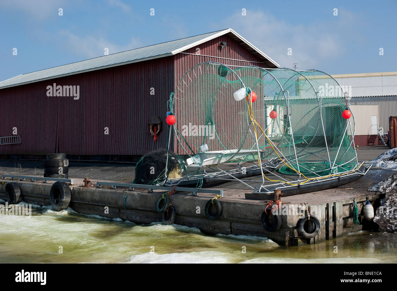 Large fish trap standing on dry land next to a wooden building in the ...