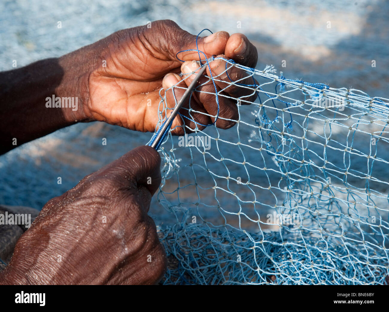 Fishermen repairing their nets beside their sea-going 