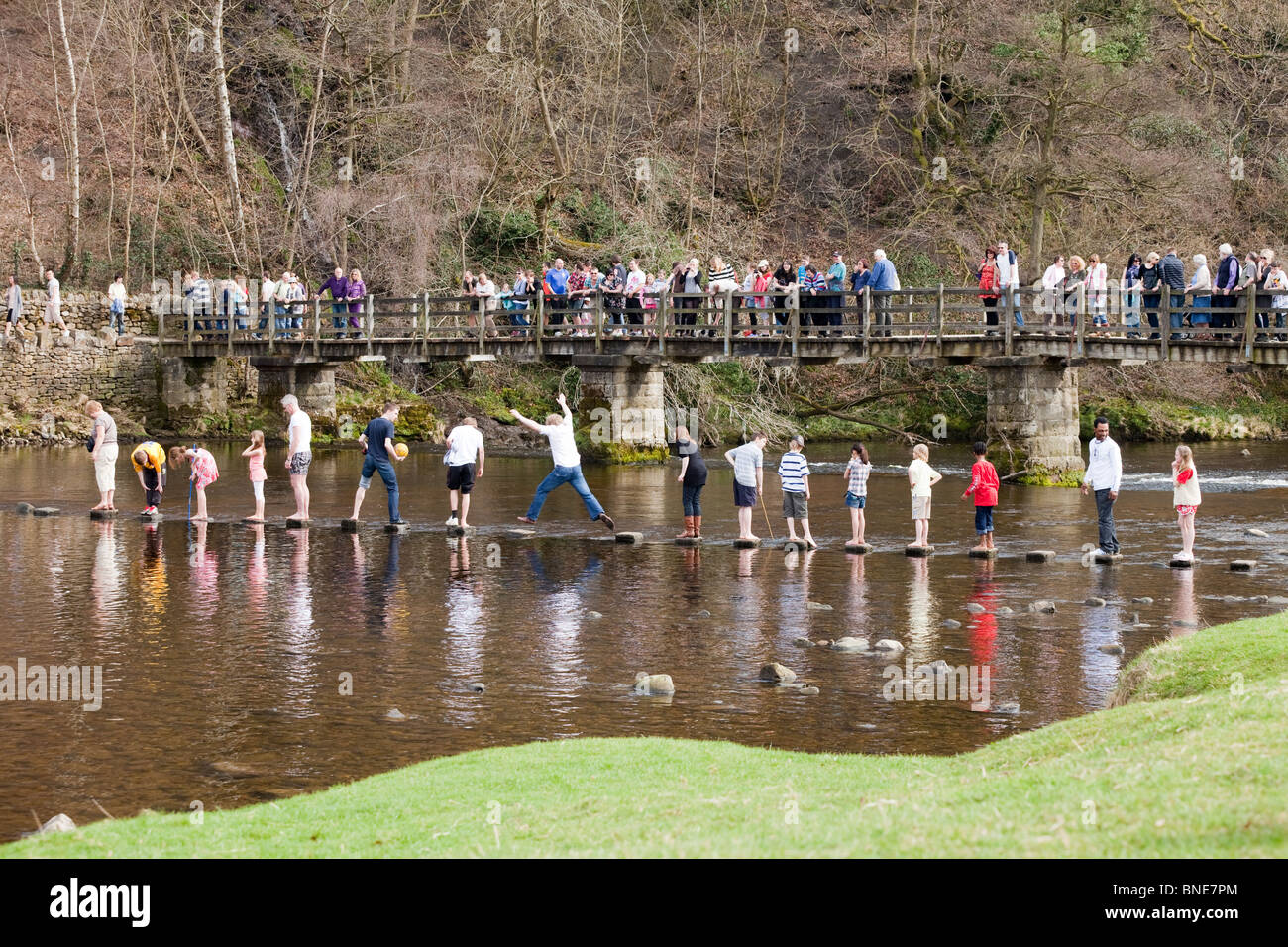 Crossing the River Wharfe via the stepping stones at Bolton Abbey, North Yorkshire UK Stock Photo