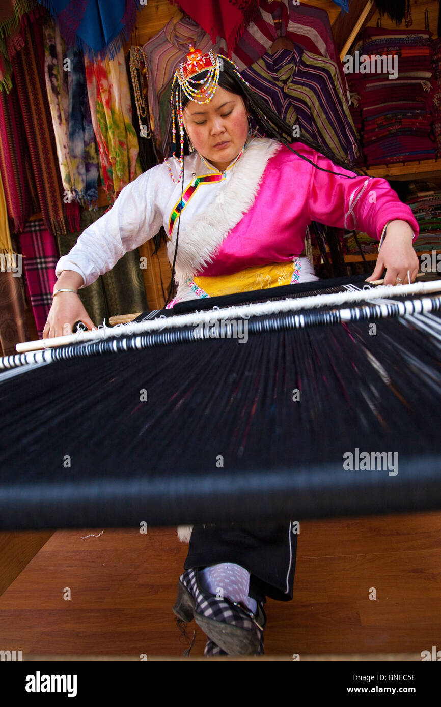 Minority woman weaving in Shangri-La or Zhongdian in Yunnan Province, China Stock Photo