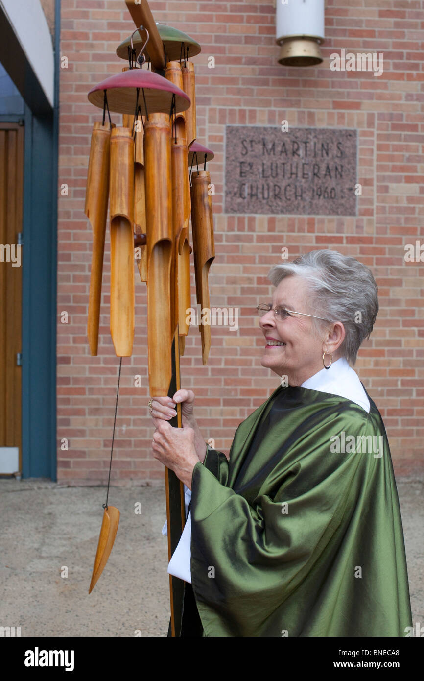 Church member in ceremonial tunic holds wooden wind chimes before