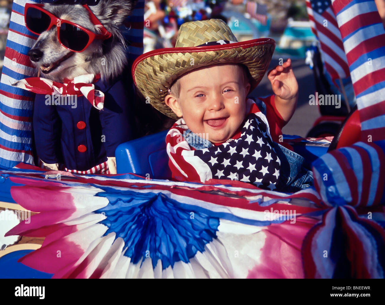Happy boy 2-3 years old with Down Syndrome waves from his 'float' in neighborhood 4th July Independence Day Patriot parade front view MR  © Myrleen Pearson Stock Photo