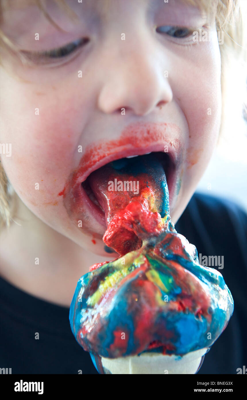 Young boy relishing a multi- flavored ice cream with unhealthy coloring agents Stock Photo