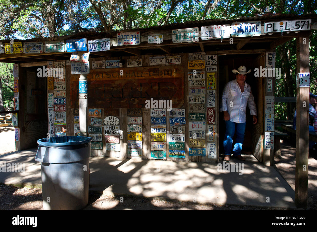 Man coming out of restroom with license plates, Luckenbach, Hill country, Texas, USA Stock Photo