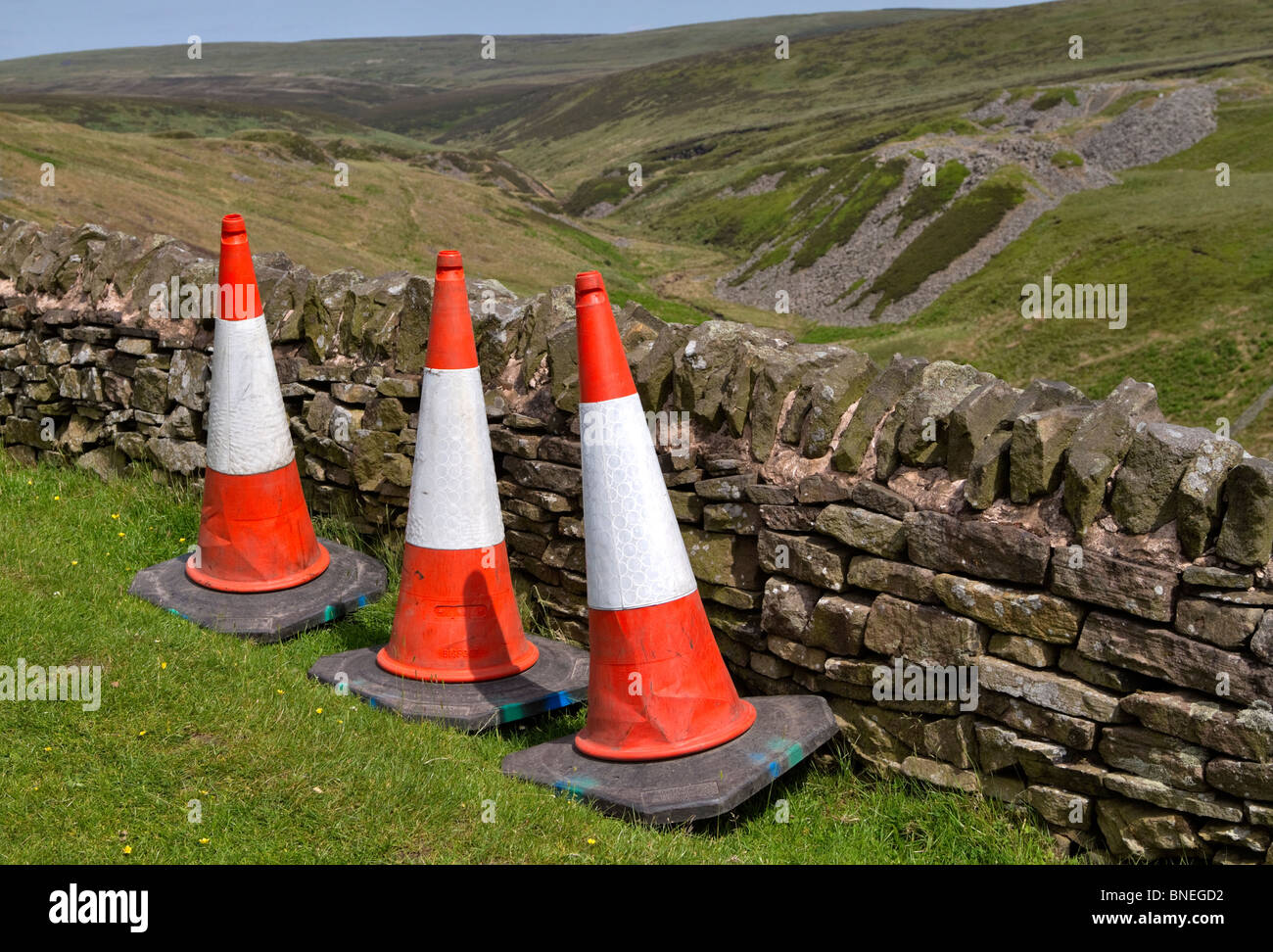 Traffic cones. Three traffic cones left beside a stone wall in the Dark Peak Area of the Peak District, Derbyshire Stock Photo