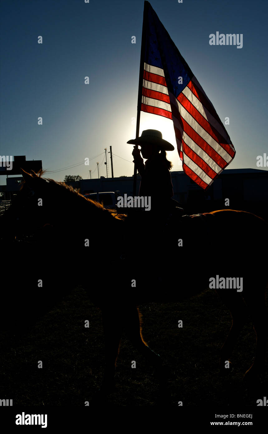 Cowgirl waving American flag at PRCA rodeo event in Texas, USA Stock Photo