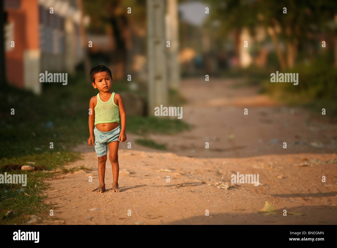 Cambodian child in shabby but bright clothes on street, editorial Stock Photo