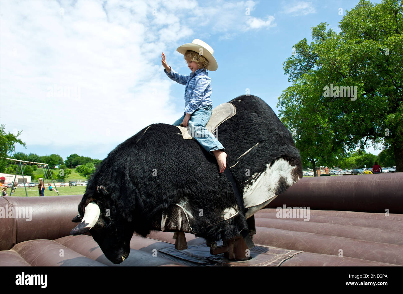 Cowboy trying his luck to stay on the mechanical bull Stock Photo
