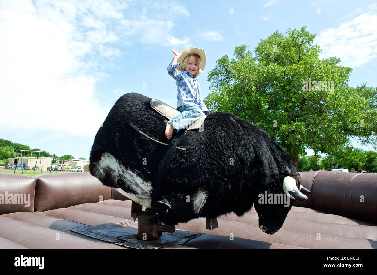 Cowboy trying his luck to stay on the mechanical bull Stock Photo