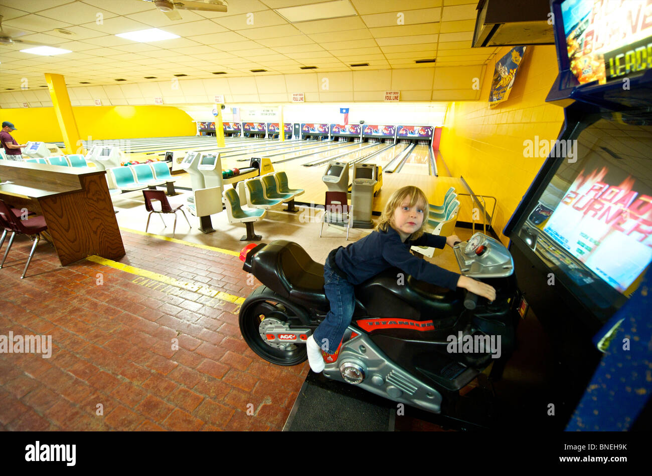 Three year old boy riding Motorcycle game in Bowling Hall Texas, USA Stock Photo