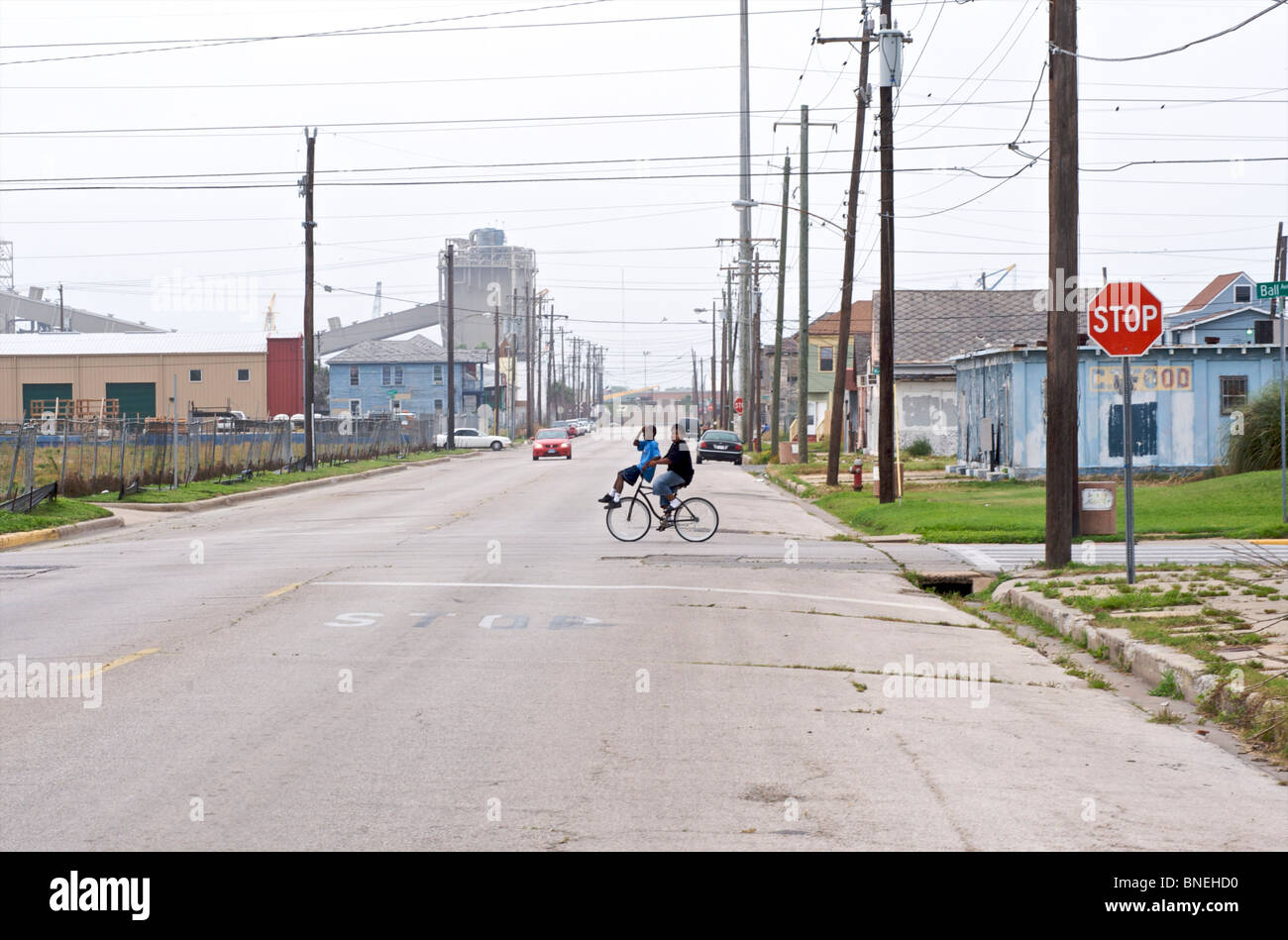 Children on bicycle crossing road near poor neighborhood in Galveston, Texas, USA Stock Photo