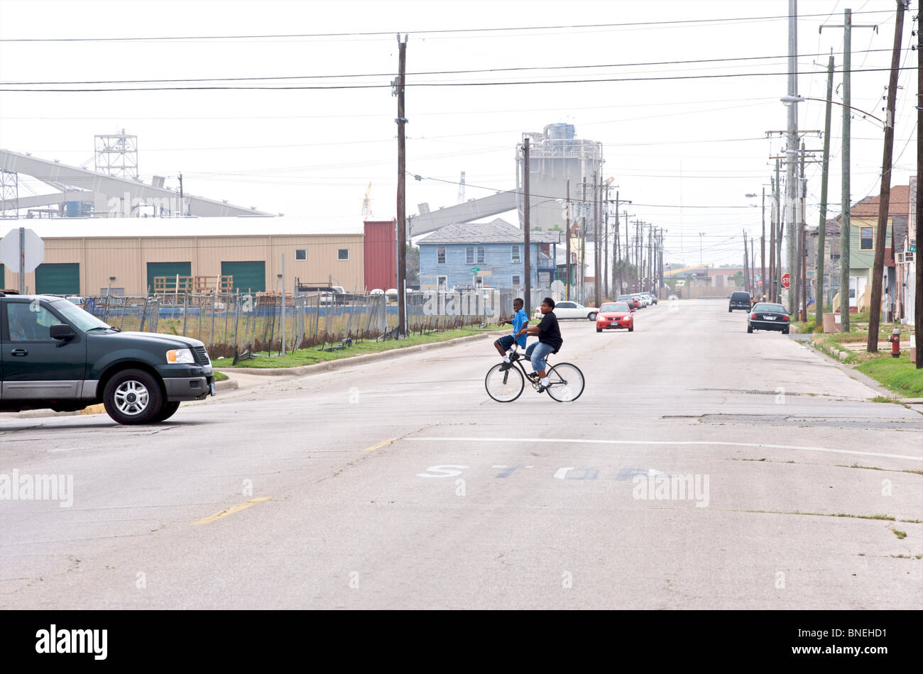 Children on bicycle crossing road near poor neighborhood in Galveston, Texas, USA Stock Photo