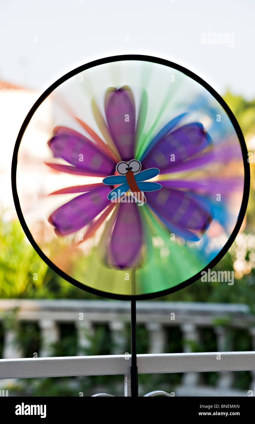 Closeup of a Childs Toy Windmill Quickly Revolving Sails in the Wind on a Veranda at a Spanish Villa Stock Photo
