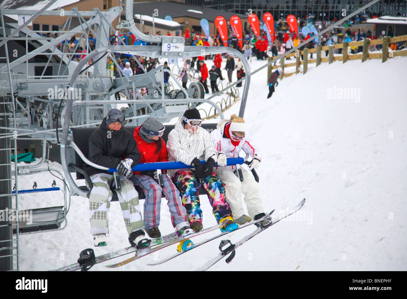 four adults sitting on the quad chairlift at peak Stock Photo
