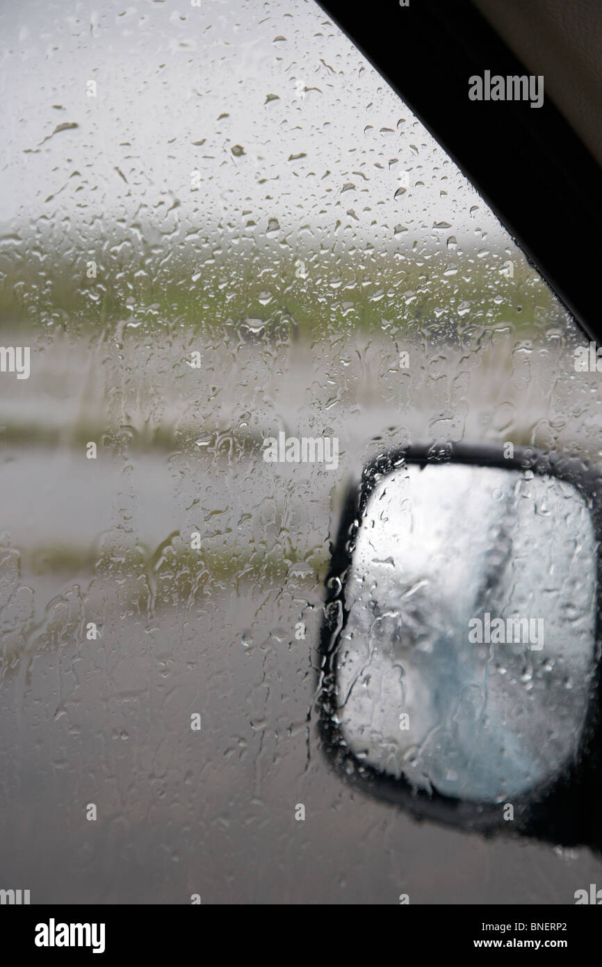 looking out through car window at rain falling on window during summer