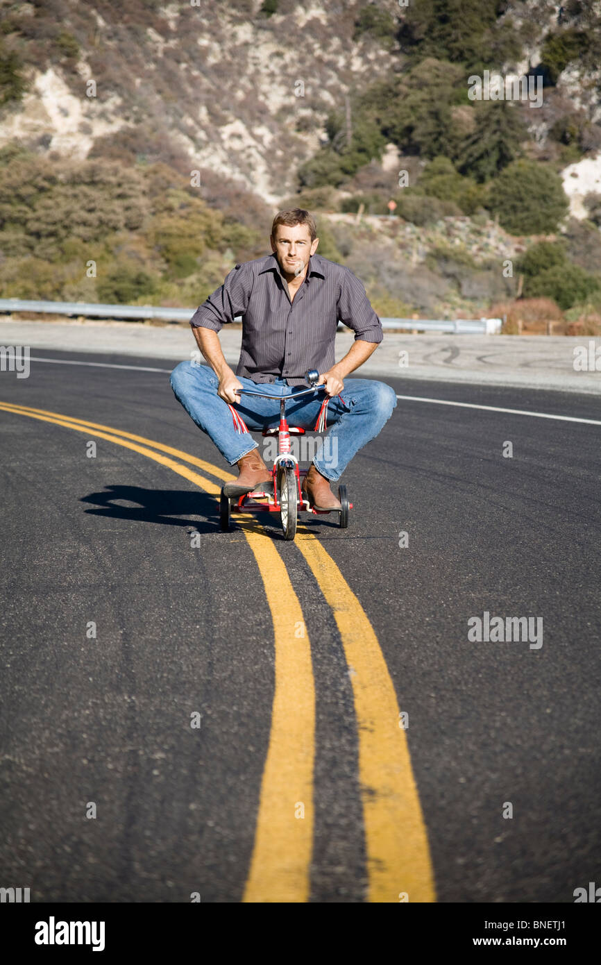 Man riding tricycle down the middle of a street Stock Photo Alamy