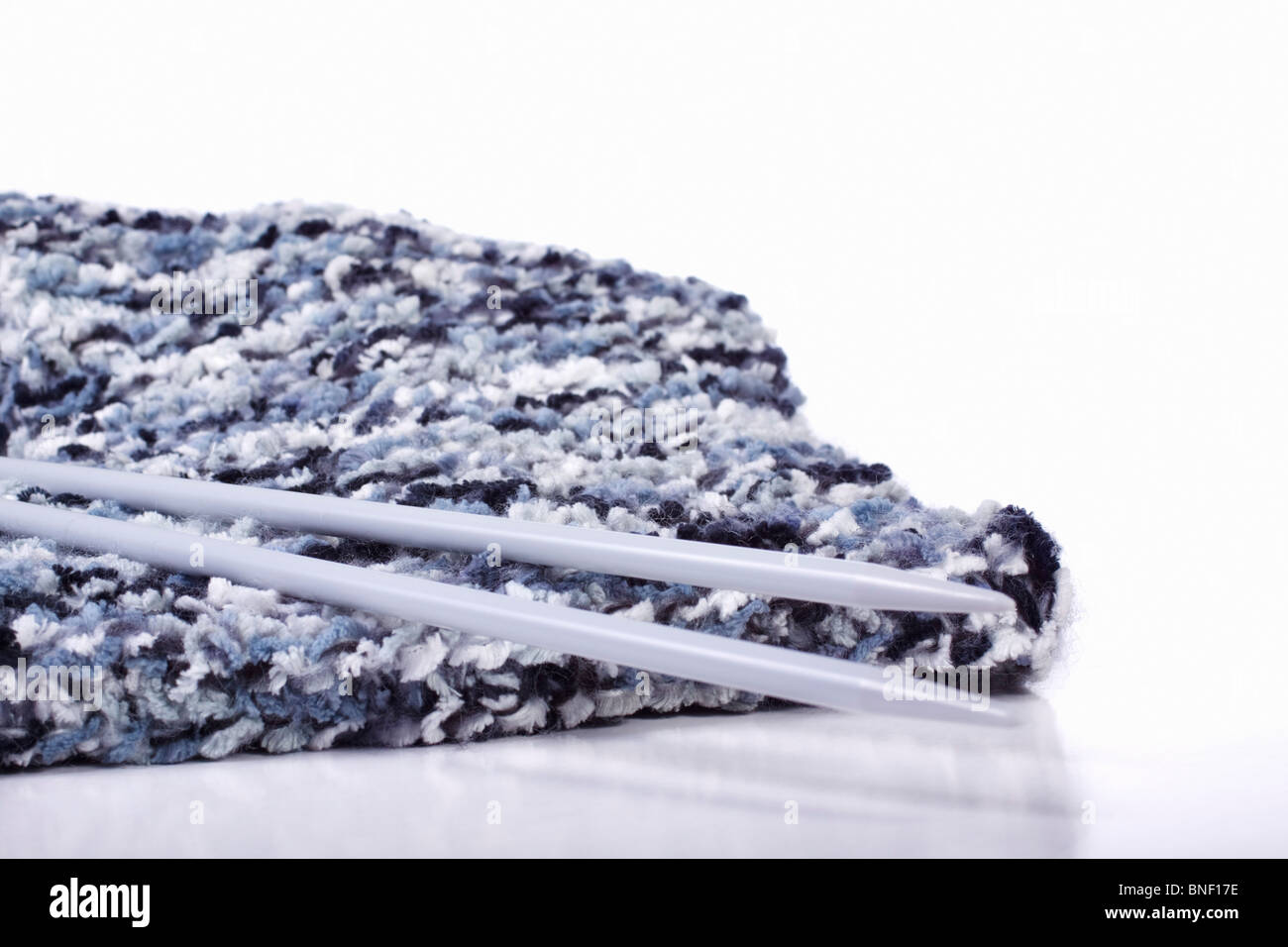 Black and grey variegated yarn scarf and knitting needles. Isolated. Stock Photo