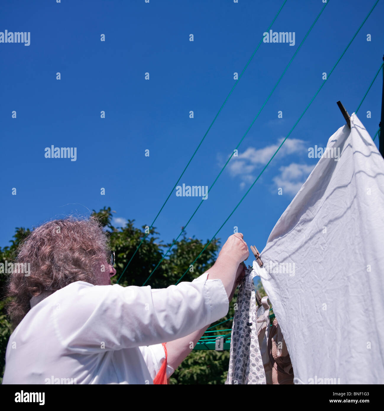 A woman hanging out her washing on a clothesline on her balcony