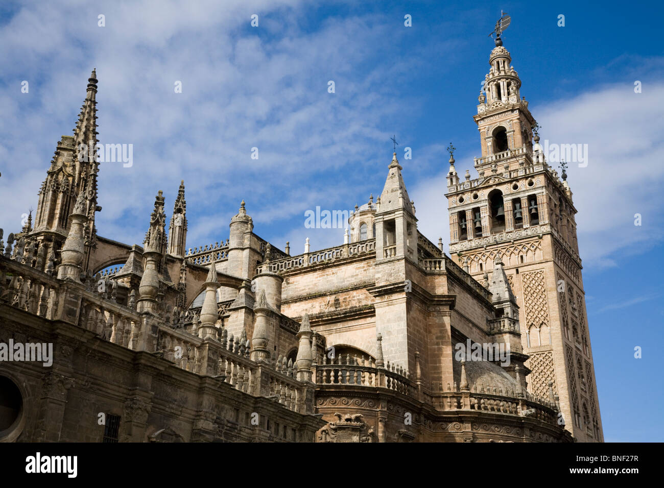 The Giralda tower (former mosque minaret converted into Cathedral bell tower) in Seville / Sevilla, & side of Seville Cathedral. Stock Photo