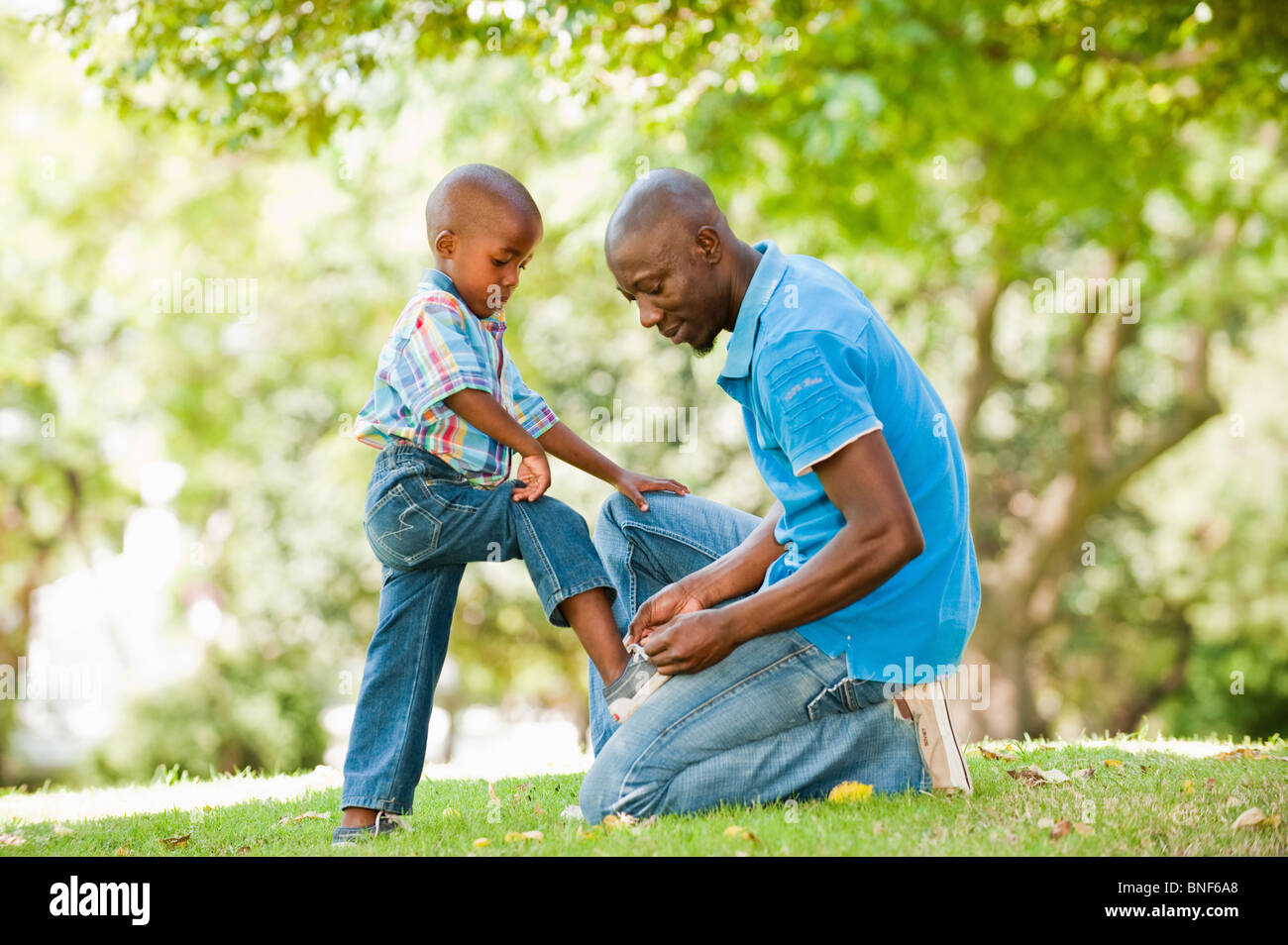 Father tying shoelace for son (4-5) in garden, Johannesburg, Gauteng Province, South Africa Stock Photo