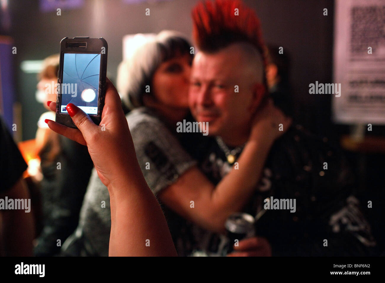 A punk couple poses to an iPhone photo at The Damned and UK Subs punk concert at the Millennium Hall in Cardiff, UK. Stock Photo