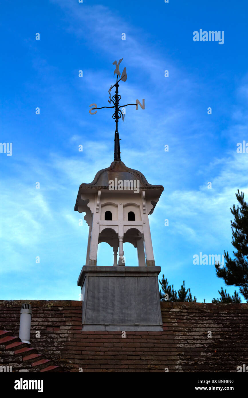 Ornate cupola with weathervane. The weather vane features a seagull design with compass points and a directional arrow. Stock Photo