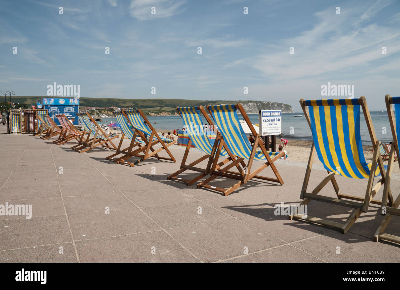 Line of deck chairs along the concrete promenade above the beach at Swanage Bay, Dorset, UK. Stock Photo