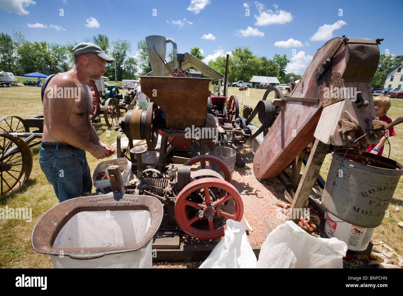 Man operating a corn shelling machine at an antique gas and steam engine show at Fort Hunter, on Erie Canal. Stock Photo